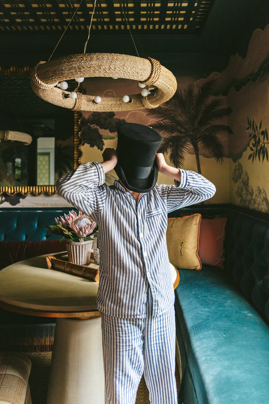 boy in bar room wearing pajamas and a top hat