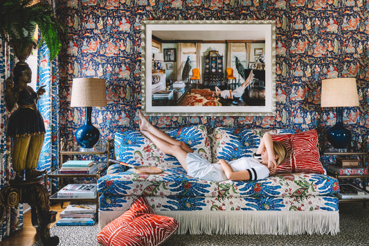 woman in tennis clothes laying on pattern sofa with art above