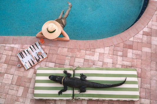 woman in pool with large hat talking to an alligator