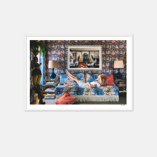 woman in tennis clothes laying on pattern sofa with art above 