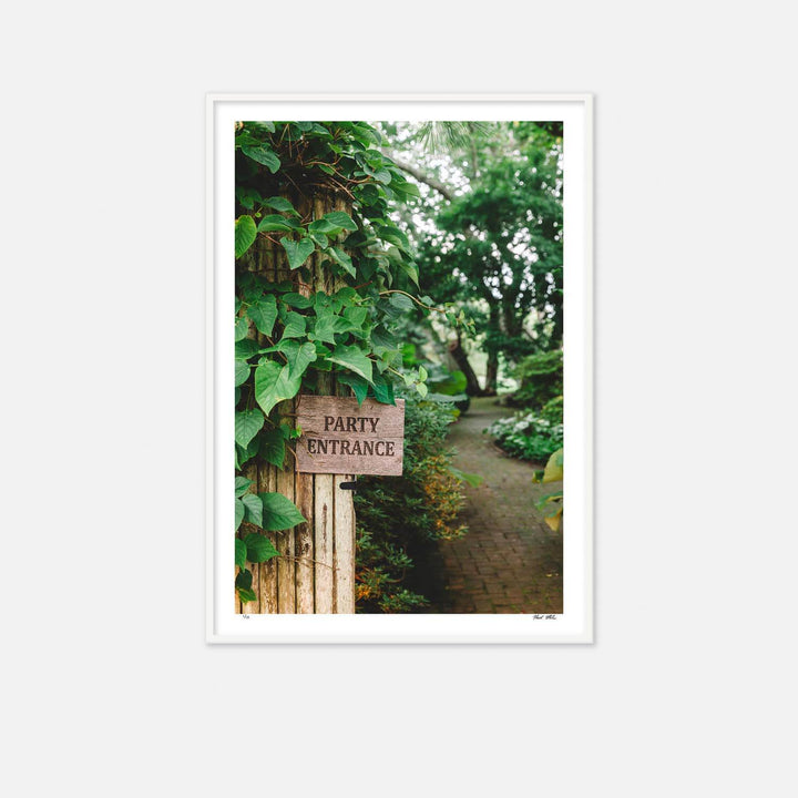 Nick Mele print, titled Party Entrance. A wooden sign pointing to 'Party Entrance' in a lush garden setting