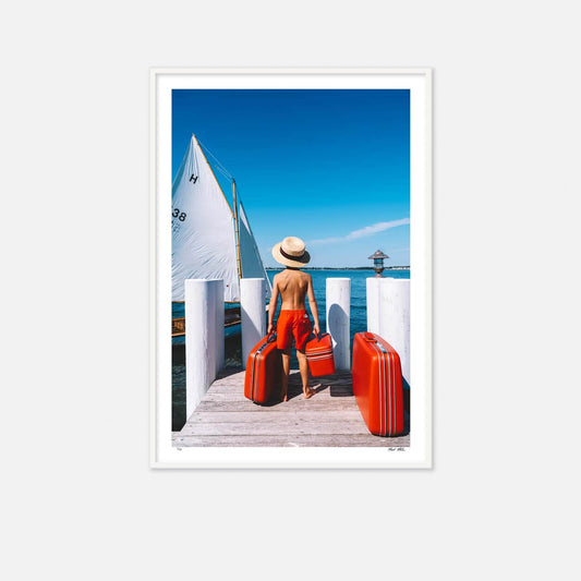 Nick Mele Print titled "Day Trip" - A little boy with red swimsuit and suitcases on a dock with a sailboat in the background