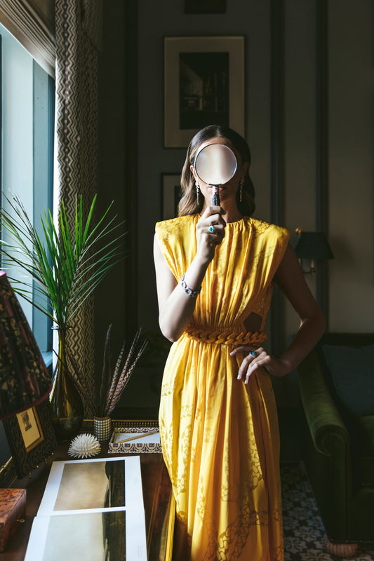 Woman in a yellow dress holding magify glass. Palm frond, palm beach, palm beach decor, palm beach style