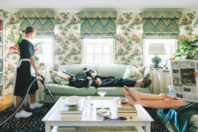 living room with lemur on green sofa with maid and lady reading the paper