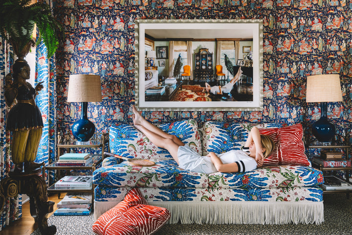 woman in tennis clothes laying on pattern sofa with art above 