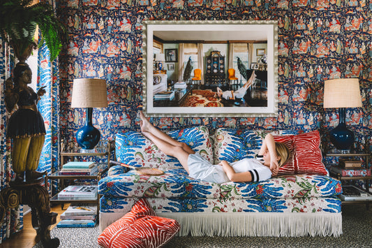 woman in tennis clothes laying on pattern sofa with art above 