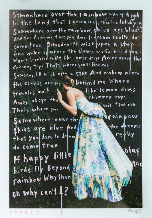 Woman in a floral dress standing in front of a blackboard with text, with a white border.