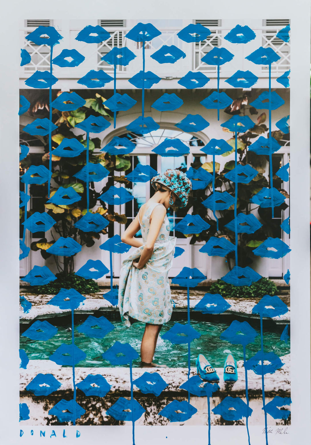 Woman standing in front of a decorative wall with blue lips and a pool.