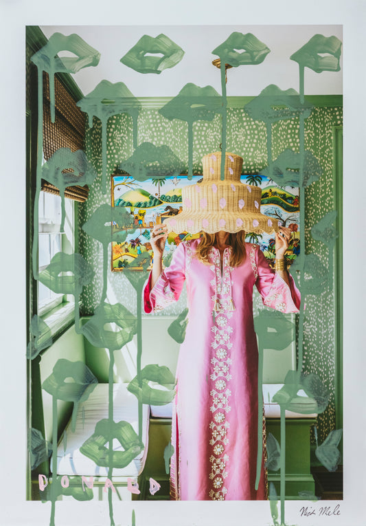 Person in a pink dress holding a cake behind a decorative green screen with floral patterns.