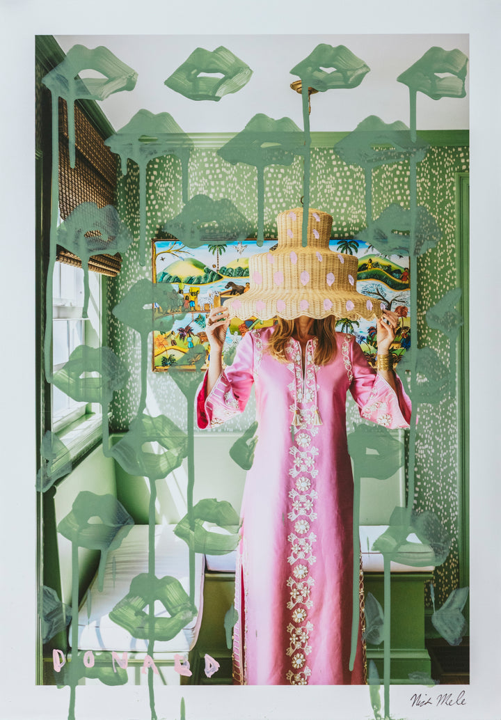 Person in a pink dress holding a cake behind a decorative green screen with floral patterns.