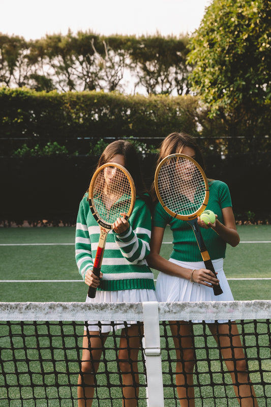 Twin girls with vintage racquets on tennis court