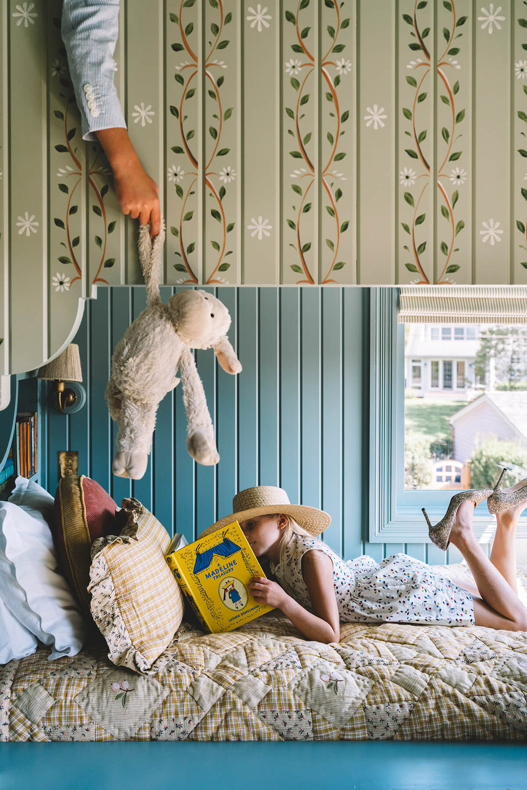 A little girl reading on bottom of bunkbed. A little boy is on the ned above trying to distract her with a teddy bear