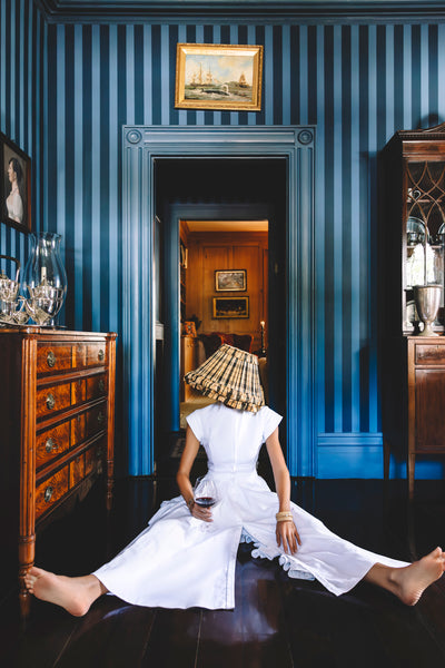 girl in white with lampshade and blue wallpaper