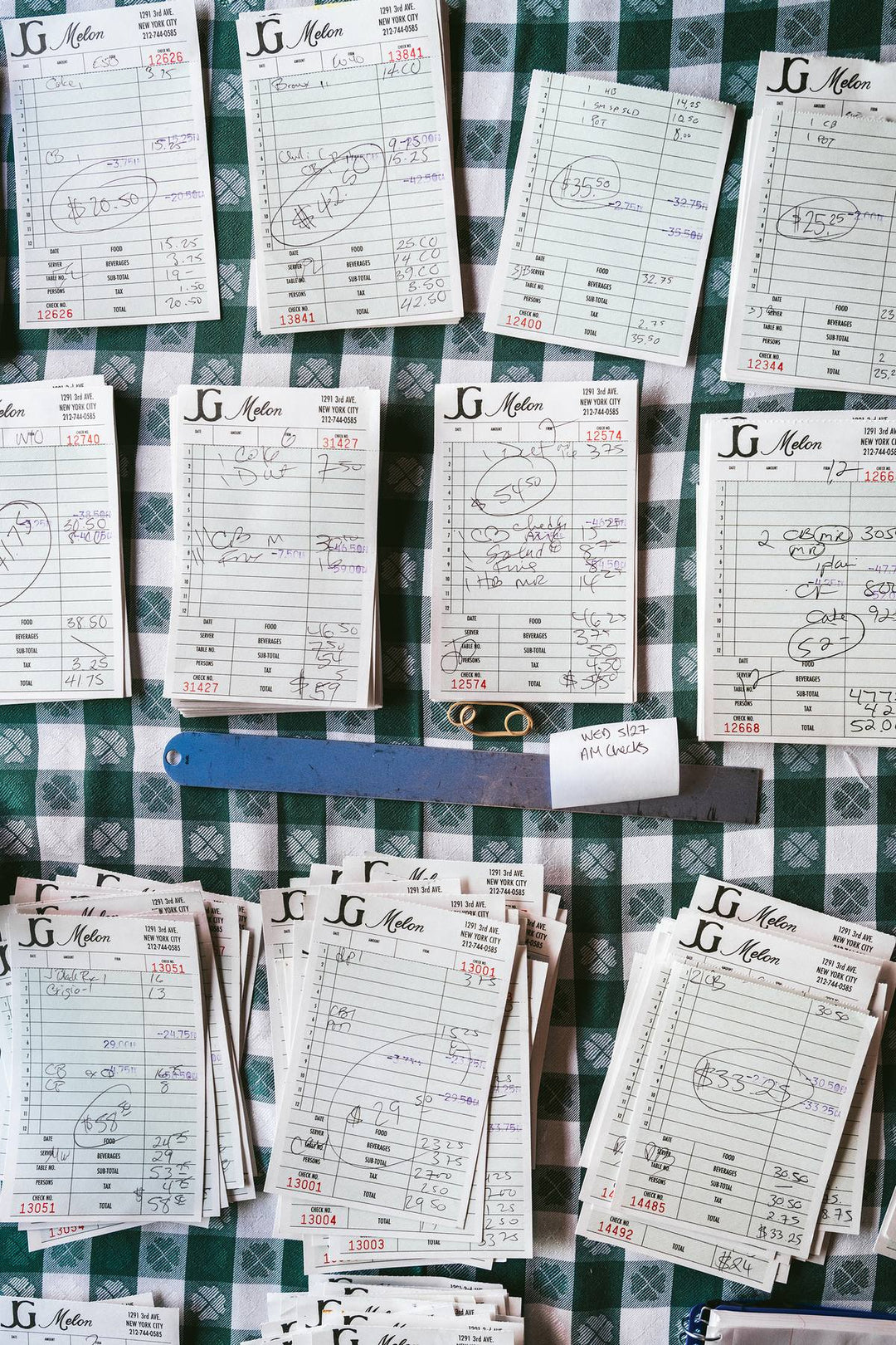 Handwritten J.G. Melon guest checks on a green gingham tablecloth. Nick Mele x Bergdorf Goodman, A New York Affair