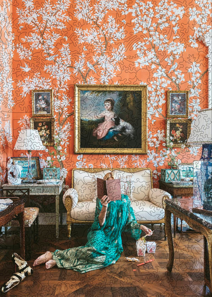 Woman in a teal caftan reads with Chinese takeout in a coral chinoiserie-papered salon. Nick Mele wooden jigsaw puzzle