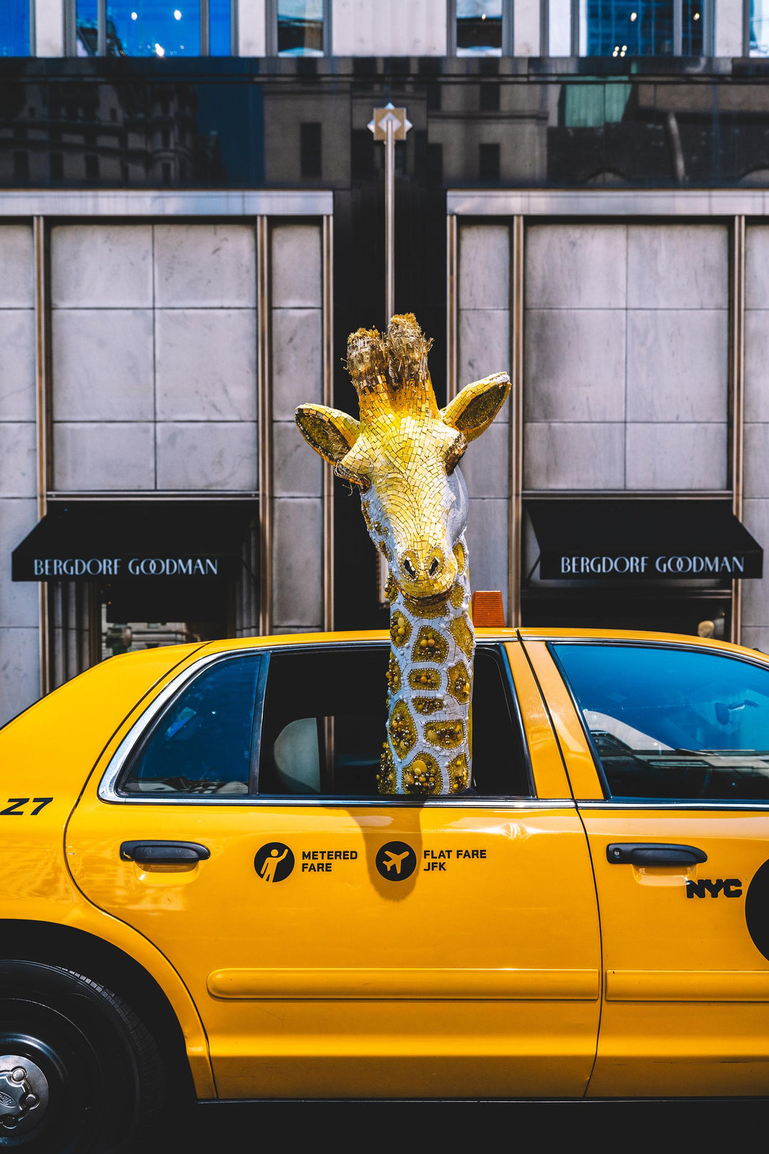 Gold giraffe sculpture rides in a yellow NYC taxi outside Bergdorf Goodman. Nick Mele x Bergdorf Goodman, A New York Affair