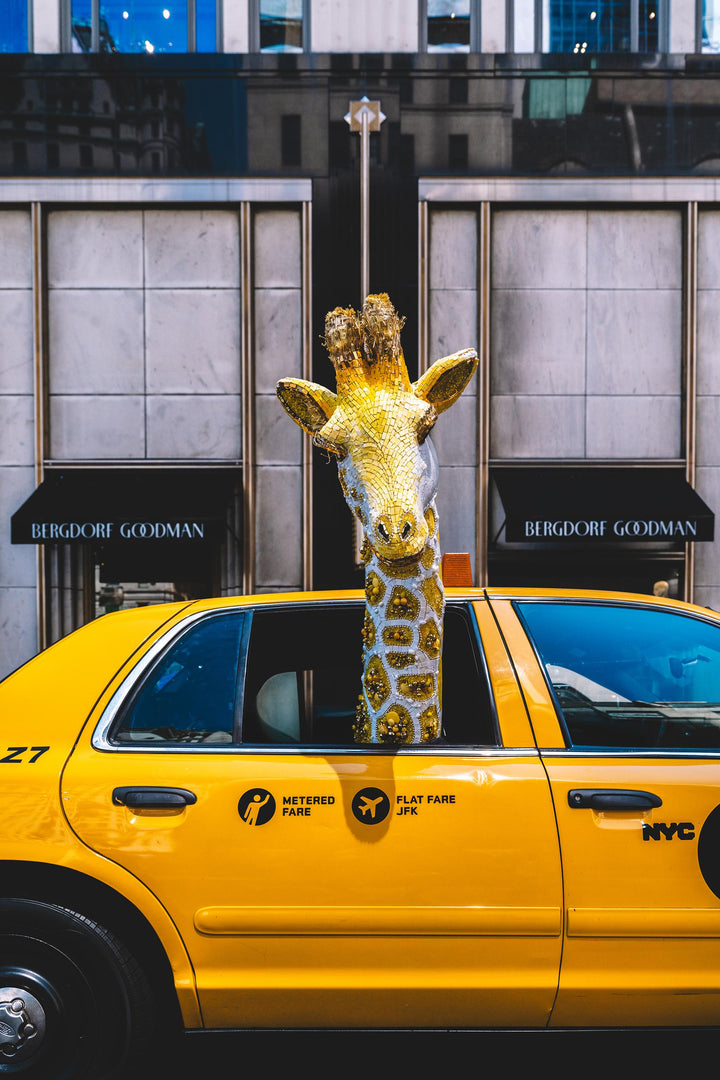 Gold giraffe sculpture rides in a yellow NYC taxi outside Bergdorf Goodman. Nick Mele x Bergdorf Goodman, A New York Affair